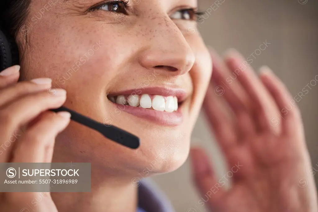 Closeup of young mixed race female call center agent wearing headset and talking to clients customers. Face of smiling and friendly customer service operator answering calls