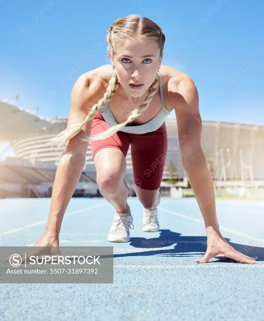 Serious female athlete at the starting line in a track race competition at the stadium. Fit sportswoman mentally and physically prepared to start running at the sprint line or starting block