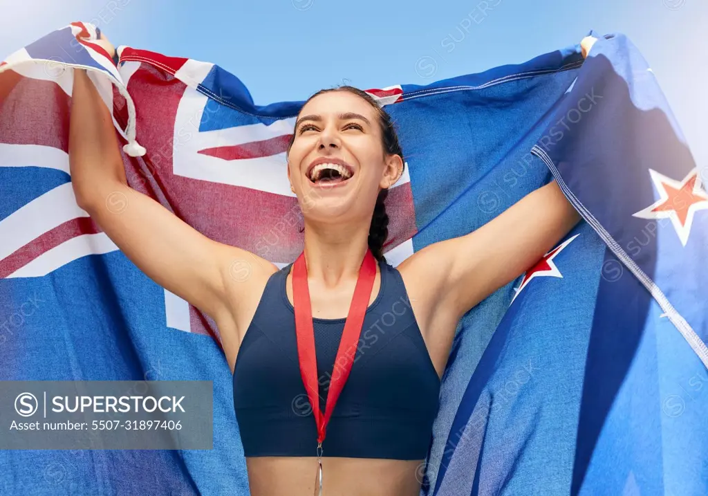 Young fit female athlete cheering and holding a New Zealand flag with a gold medal after competing in the Olympics. Smiling active sporty woman feeling motivated and celebrating winning in sport