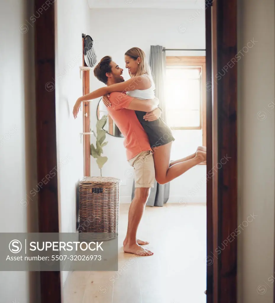 Happy young boyfriend holding girlfriend in arms as he lifts her up while  they look into each others eyes and share intimate moment. Romantic young  couple hugging and enjoying passionate dance at