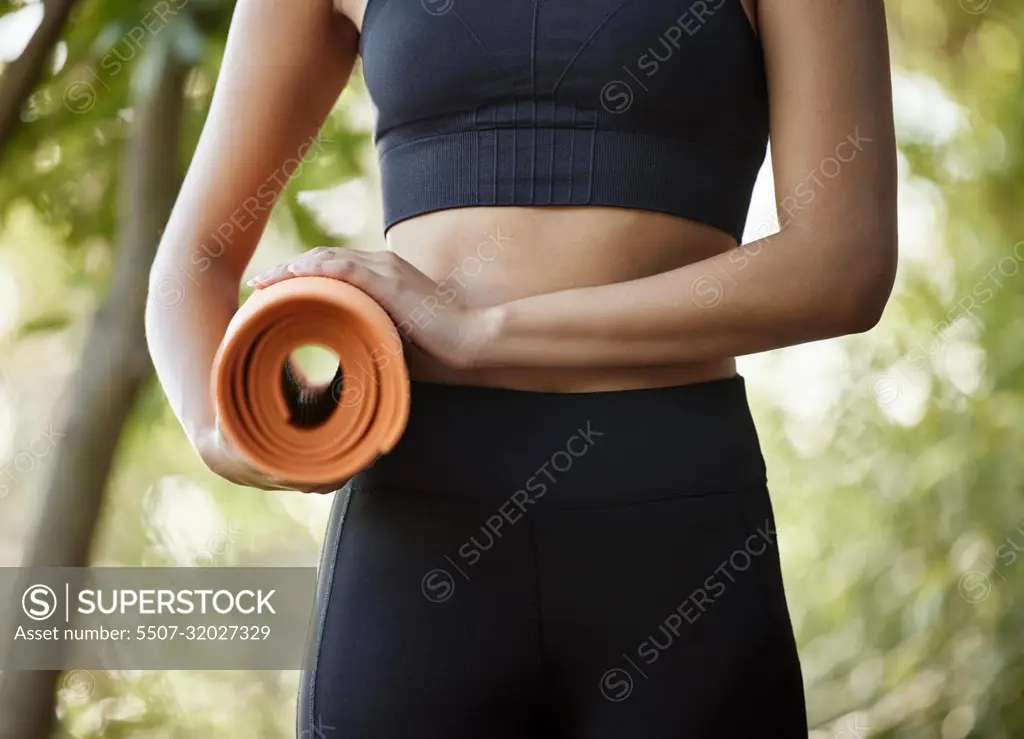 Off to yoga class. an unrecognizable young female athlete standing with her yoga mat outdoors.