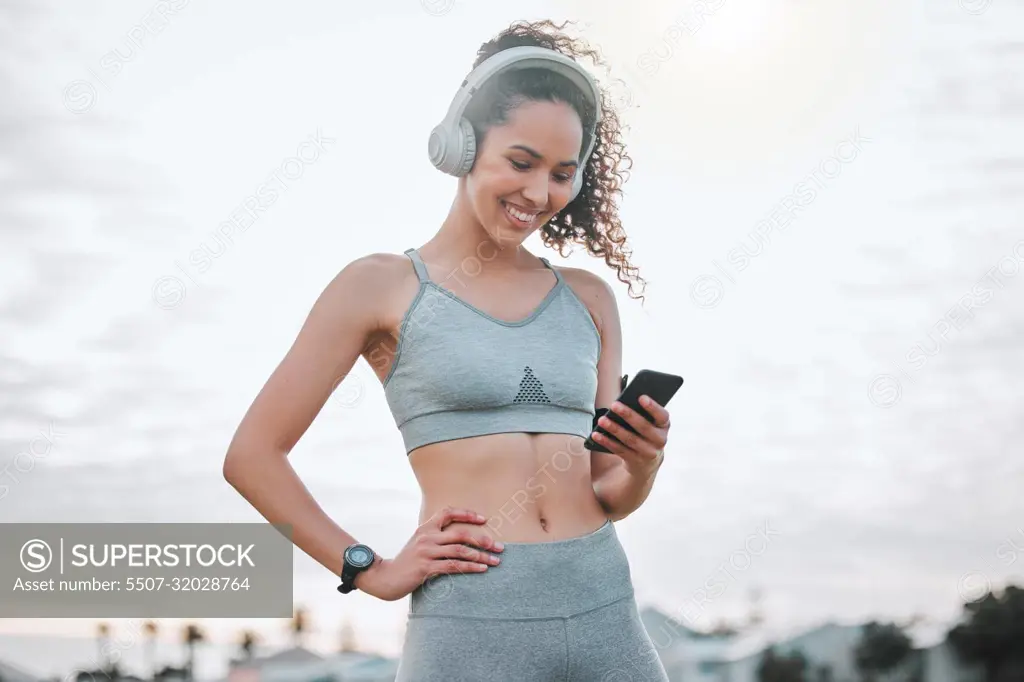 Tracking her personal progress. an attractive young female athlete exercising outdoors.