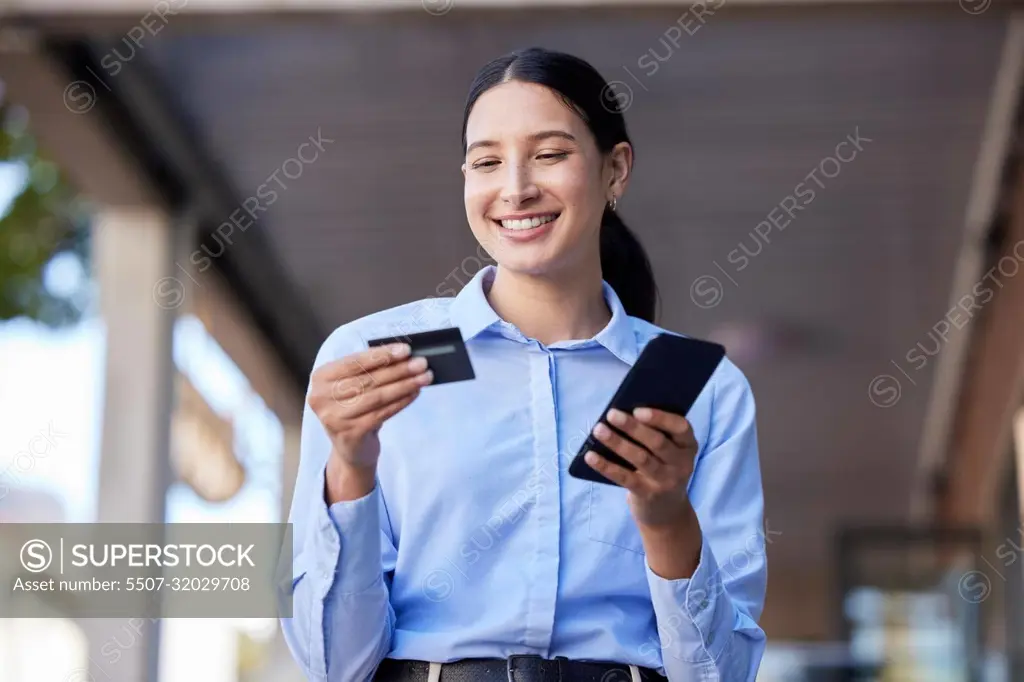 Young mixed race happy businesswoman using a credit card and phone to shop online. One hispanic woman paying for a purchase using her phone. Woman buying products using her phone and bank card