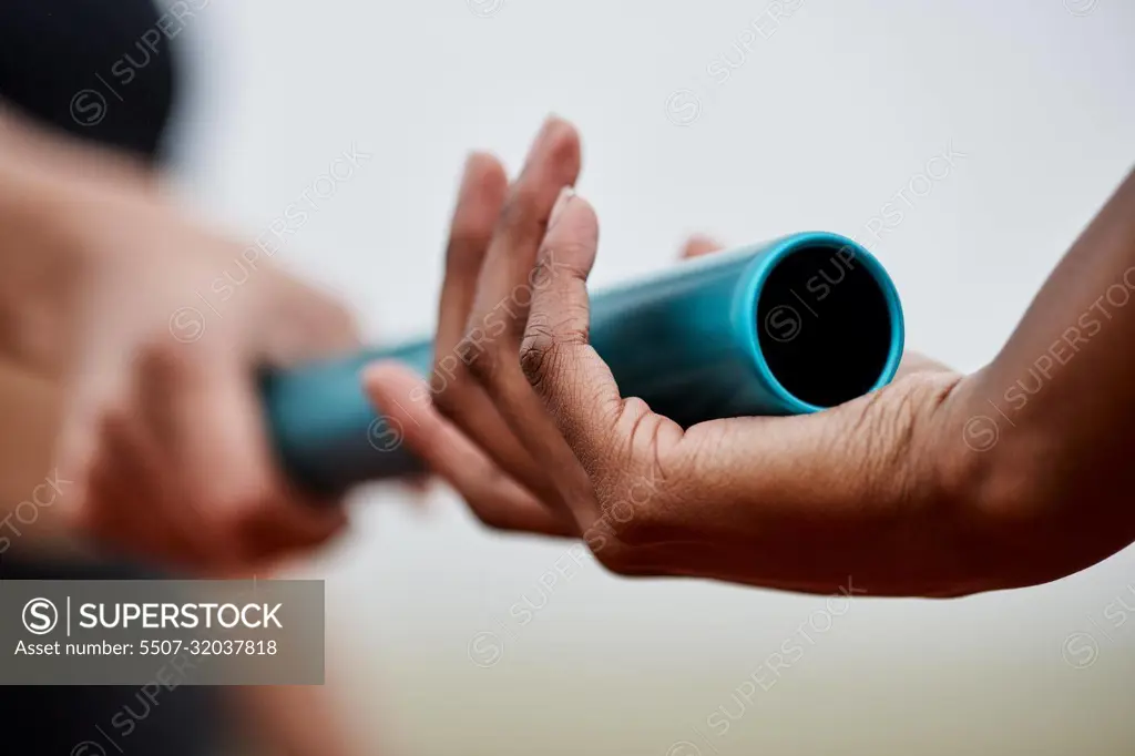 Take it and run. two athletes passing a baton during a relay race.