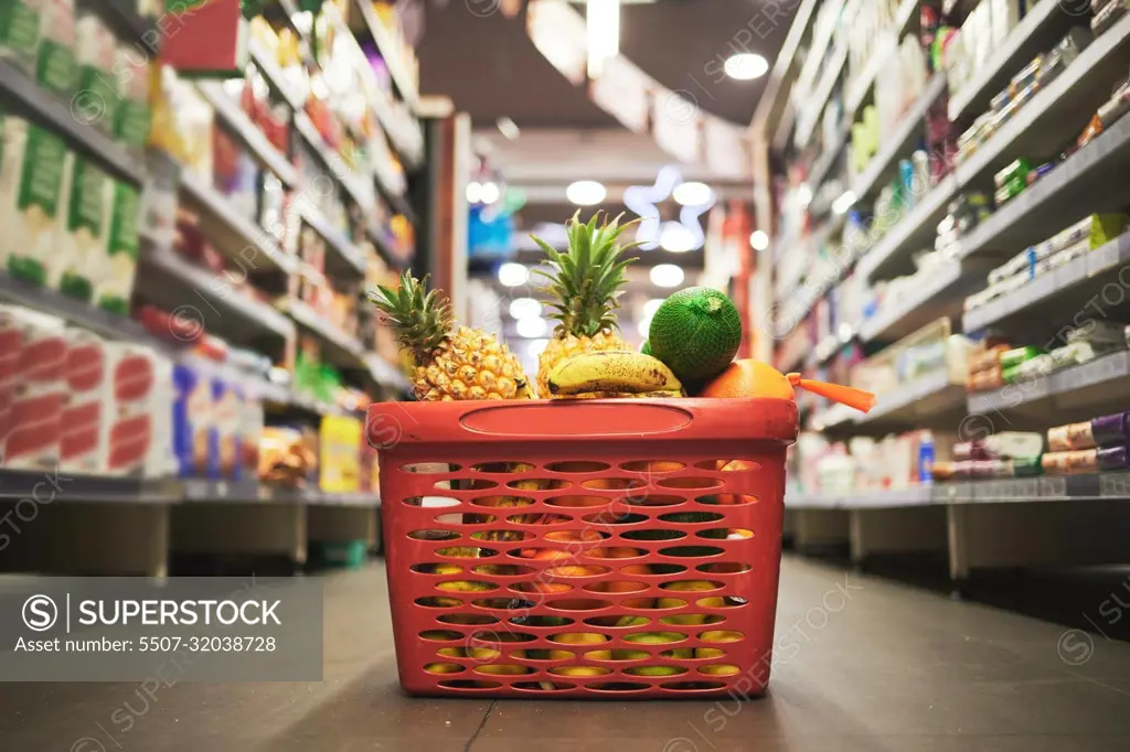 Supermarket, market or grocery store aisle with basket of quality choice, healthy fruits and vegetables. Buying retail sale items in a shopping cart. Group of consumables or food products on floor