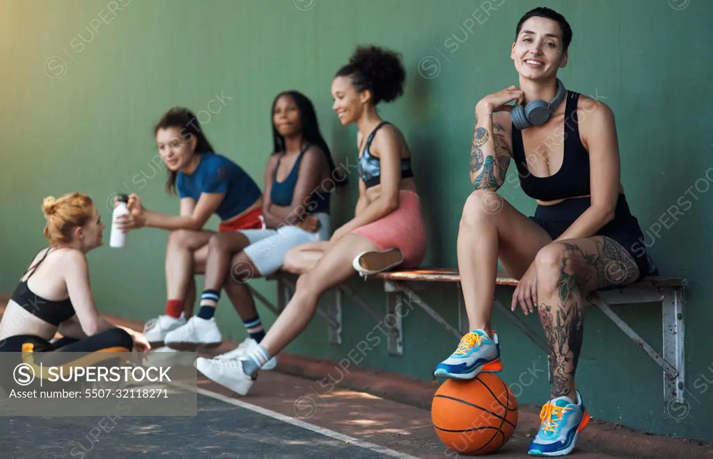 Chilling after another victory. Full length portrait of an attractive young female athlete sitting on a bench at the basketball court with her teammates in the background.