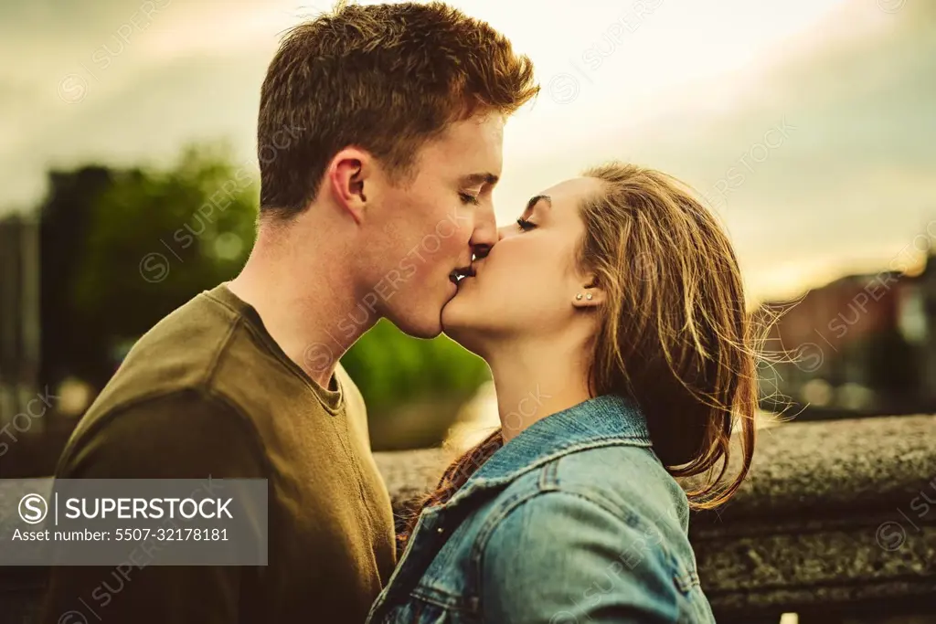 They are very much in love. a loving young couple sharing a kiss while out on a date.