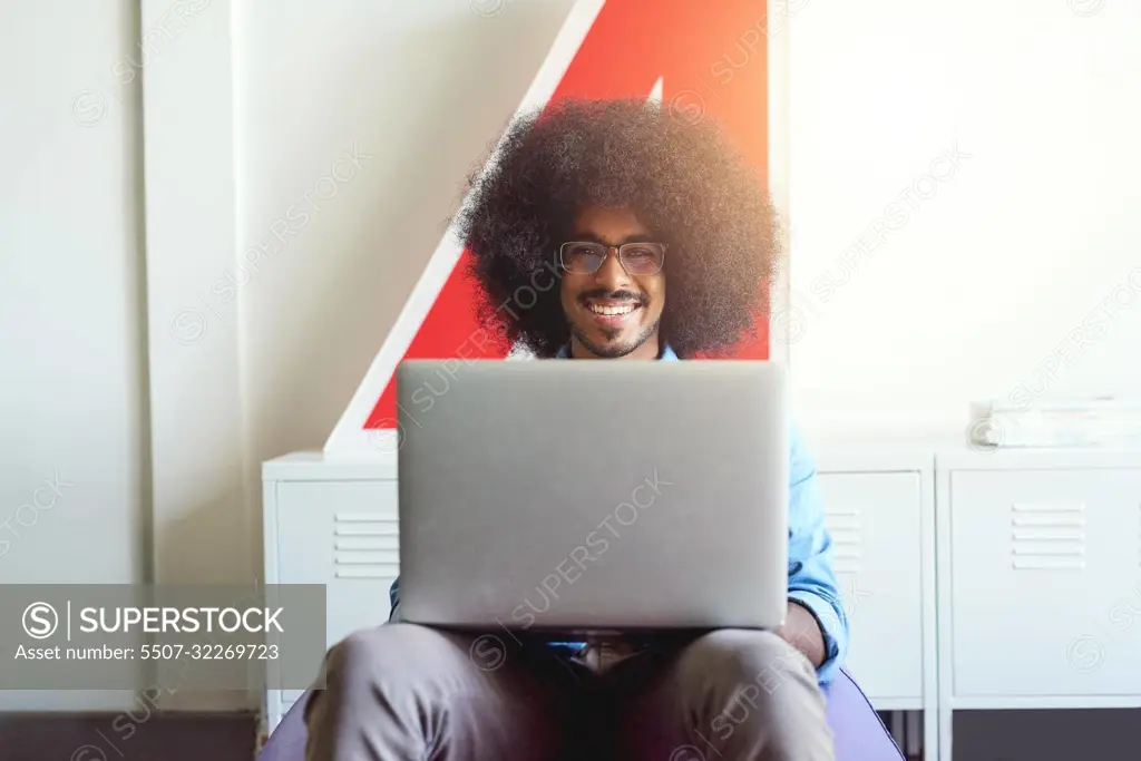 Getting his work done anywhere in the office. a young creative employee using a laptop in a modern office.