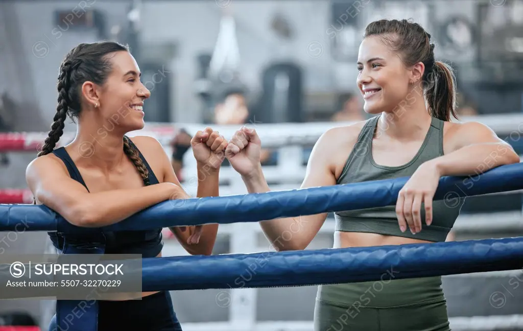 Giving support, motivation and bumping fists after being active, exercising and training in ring. Team of female boxers, fighters or sports athletes standing together in a gym, fitness center or club