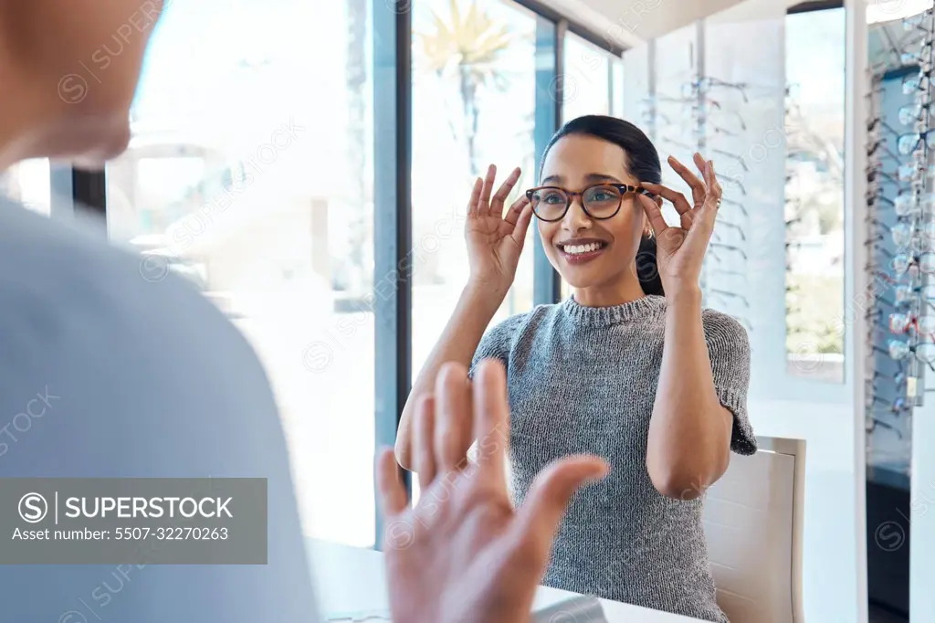 A customer buying, testing or trying on glasses at an optometrist store or shop. Health care eye wear professional picking or selling a pair of new eyeglasses to a young female client or patient.