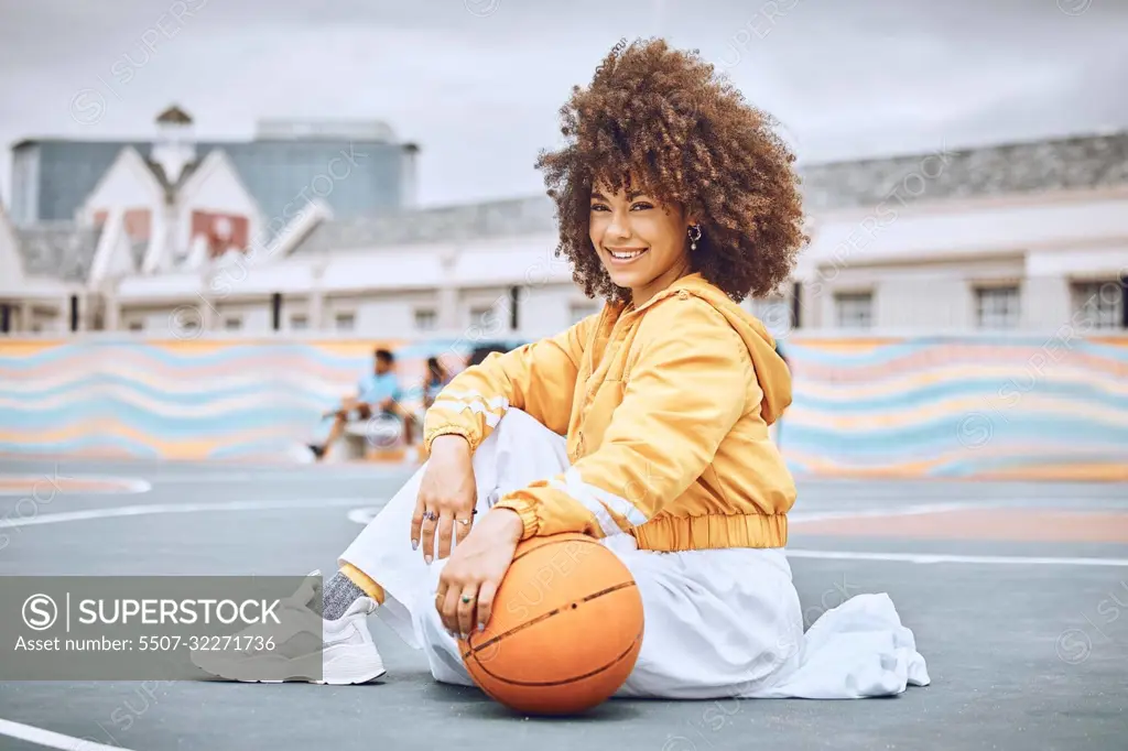 Beautiful, young and female basketball coach with an afro sitting on the court outside. Portrait of a professional, confident and healthy athlete woman in sports, health and fitness.