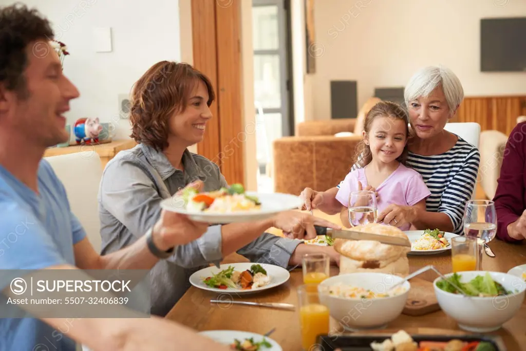 Everybody dig in. a multi generational family having a meal together around a dining table.