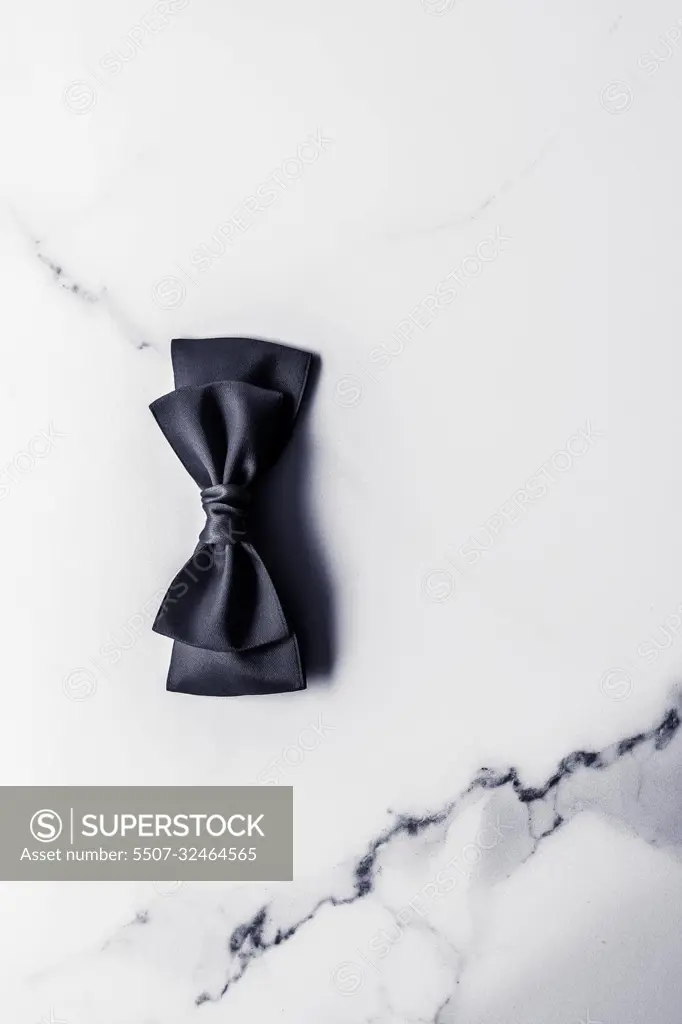 Black silk ribbon and bow on marble background, flatlay, Stock image