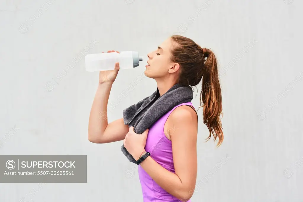 Water is an important part of exercise. an attractive young female athlete drinking water against a grey background.