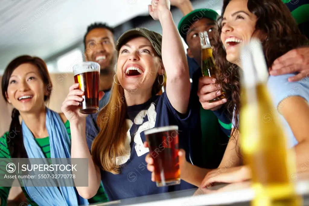 Drinks and sports with friends. A group of excited friends cheering on their favourite team at the bar.