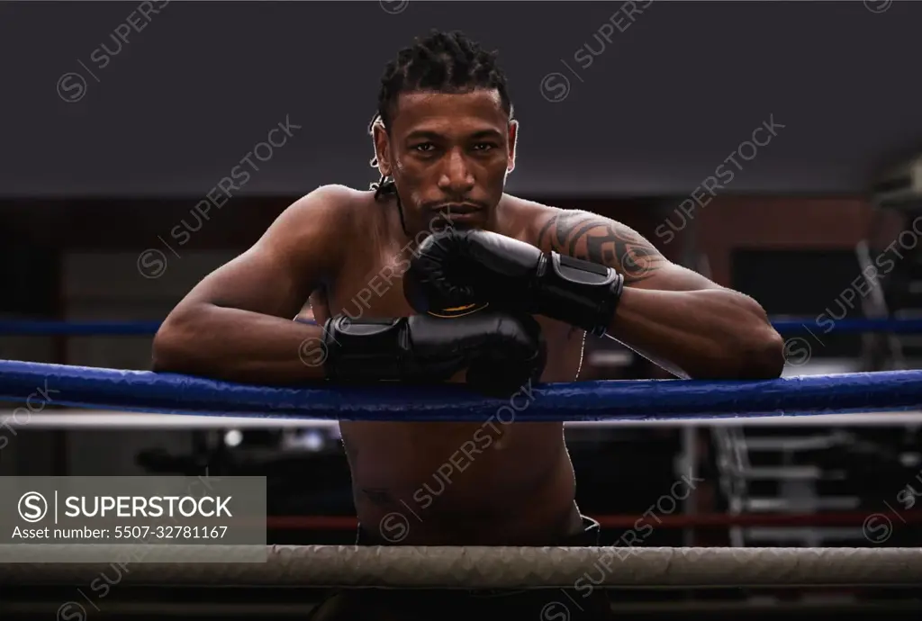 I own this ring. Portrait of a young boxer leaning on the ropes of a boxing ring.