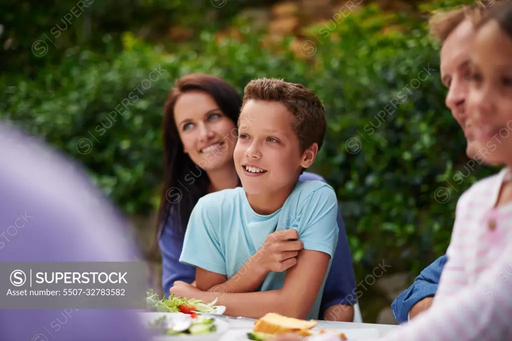 Family and laughter. a happy multi-generational family having a meal together outside.