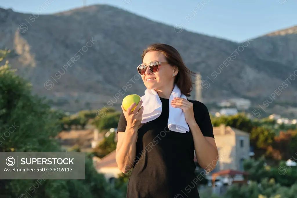 Smiling mature woman eating green apple, diet healthy food