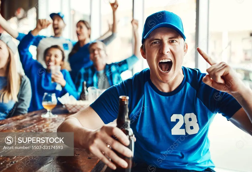 Our team will remain undefeated. Portrait of a man holding up one finger while watching a sports game with friends at a bar.