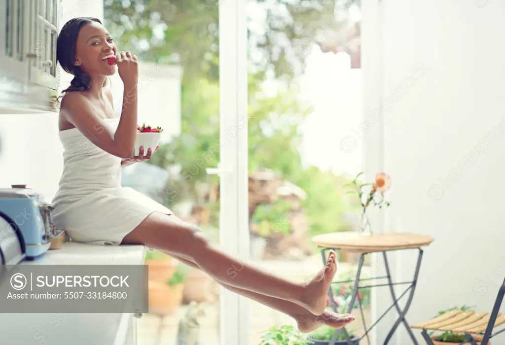 Enjoying a healthy and delicious snack. A young woman eating strawberries.