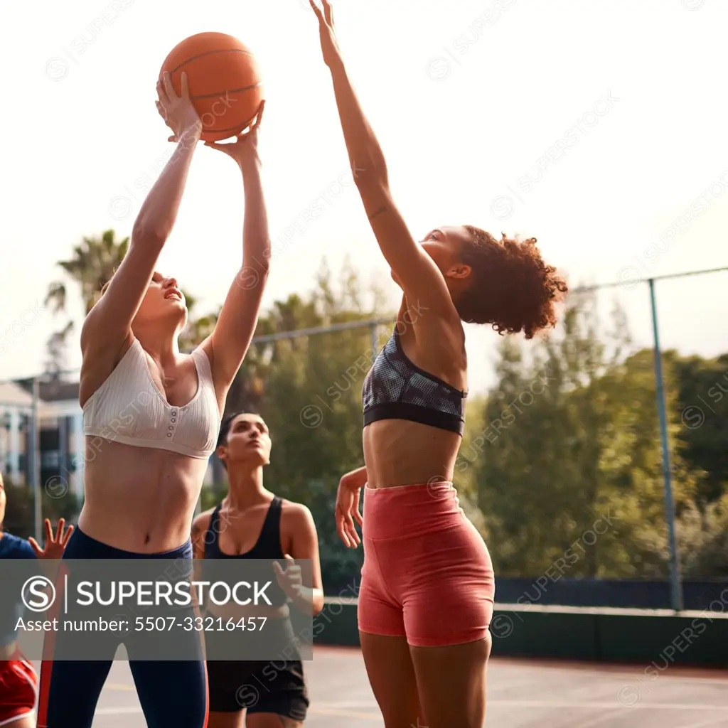 Trying my luck here. a diverse group of sportswomen playing a competitive game of basketball together during the day.