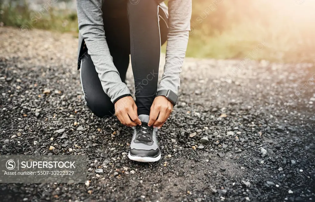 Closeup, fitness and woman outdoor, tie shoes and cardio workout for training, run and exercise. Zoom, female person or athlete start with practice, hands and runner outside for a marathon and sports