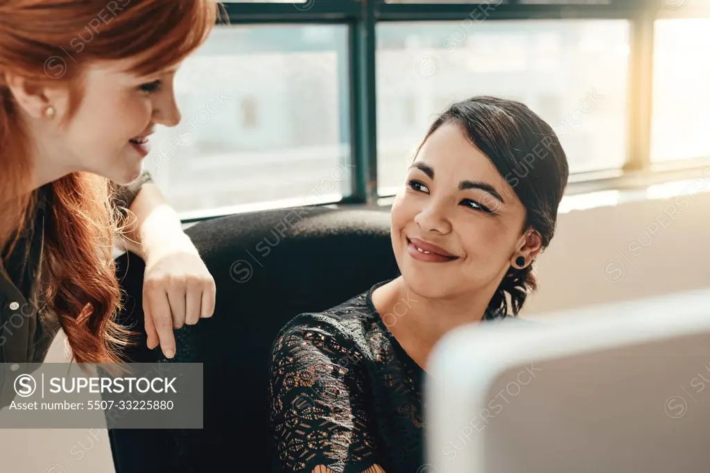 Thats why I love working with you. two young businesswomen using a computer together in a modern office.