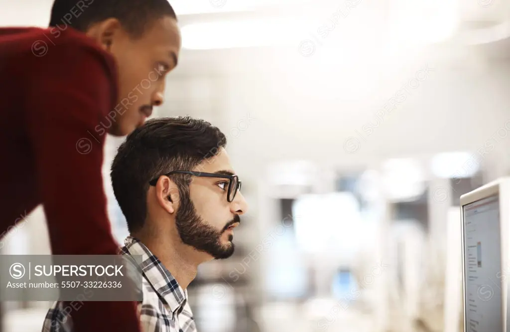 Putting in the hard work to secure their future. two university students working together on a computer in the library on campus.