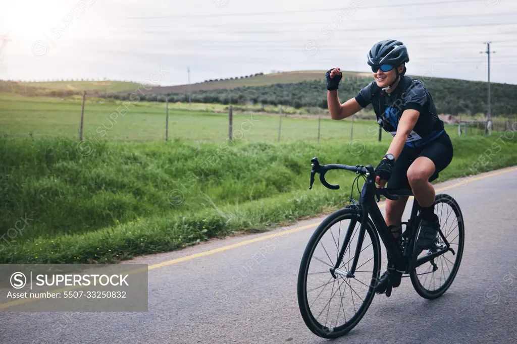 Fitness, win and woman in celebration while cycling in nature with energy for a race, marathon or competition. Sports, workout and female athlete cyclist cheering for cardio exercise on outdoor road.