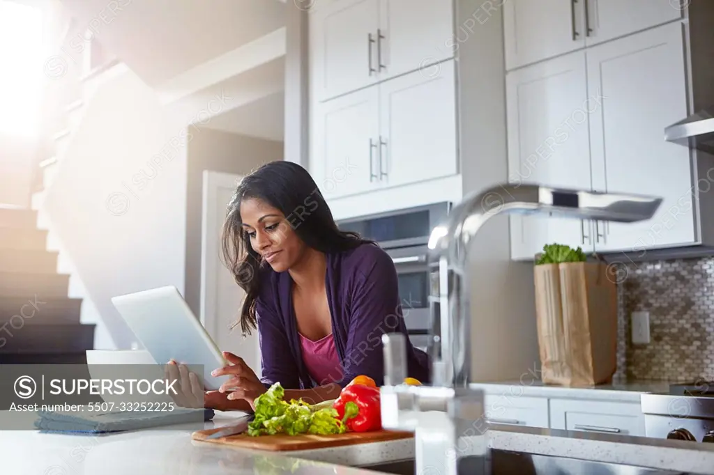 Its never been easier to stay healthy. a young woman using a digital tablet while preparing a healthy meal at home.