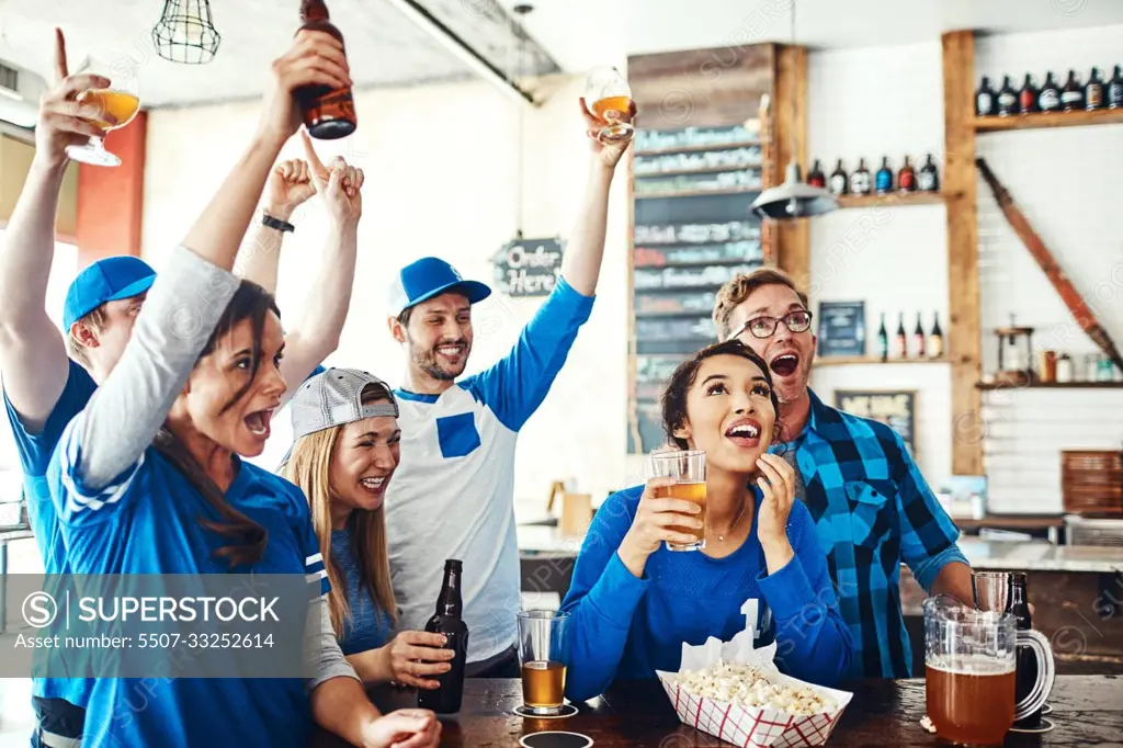 Die hard sports fans. a group of friends cheering while watching a sports game at a bar.