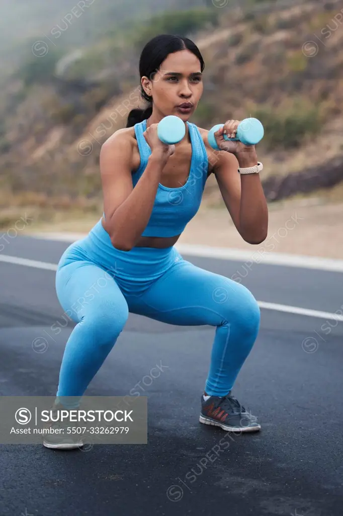 Fitness, outdoor and woman doing a exercise with weights for strength, wellness and health. Sports, cardio and young female athlete doing a workout or training with equipment in nature in the road.