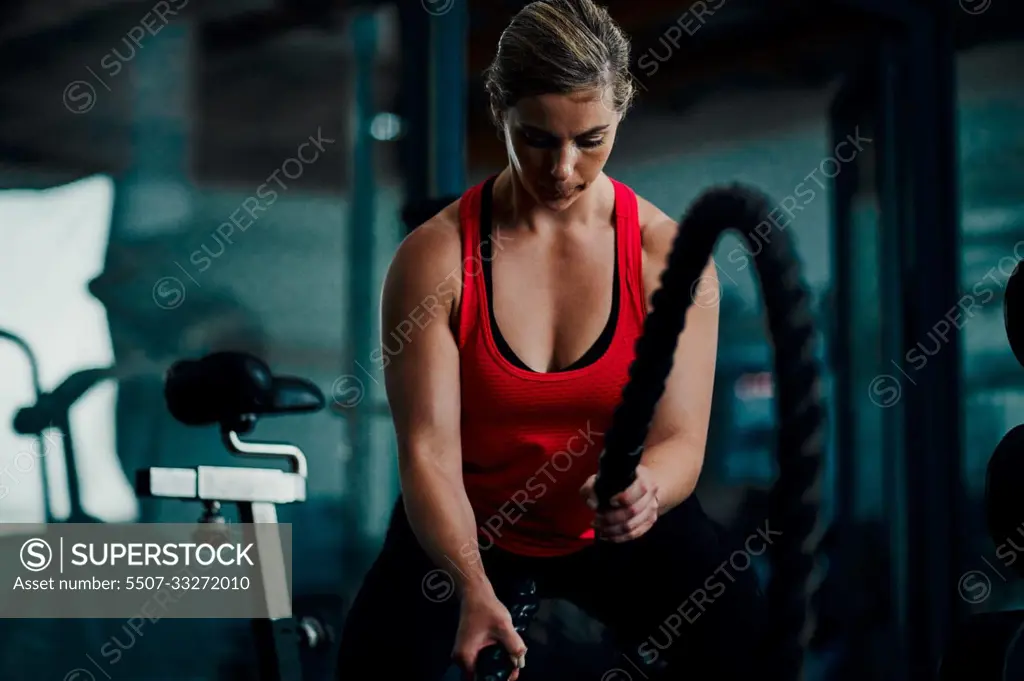 Ready for battle. an attractive young female athlete working out with battle ropes in the gym.