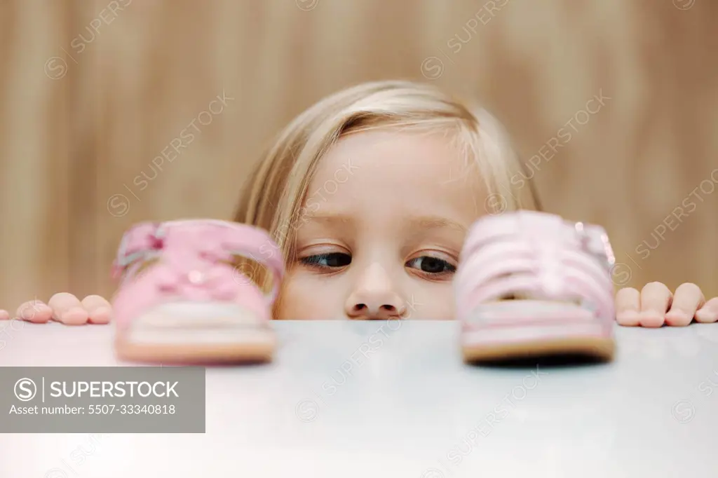 Kids, fashion and shoes with a girl choosing between footwear while shopping in a retail store. Children, cute and choice with a young female child deciding what shoe to buy for her home wardrobe