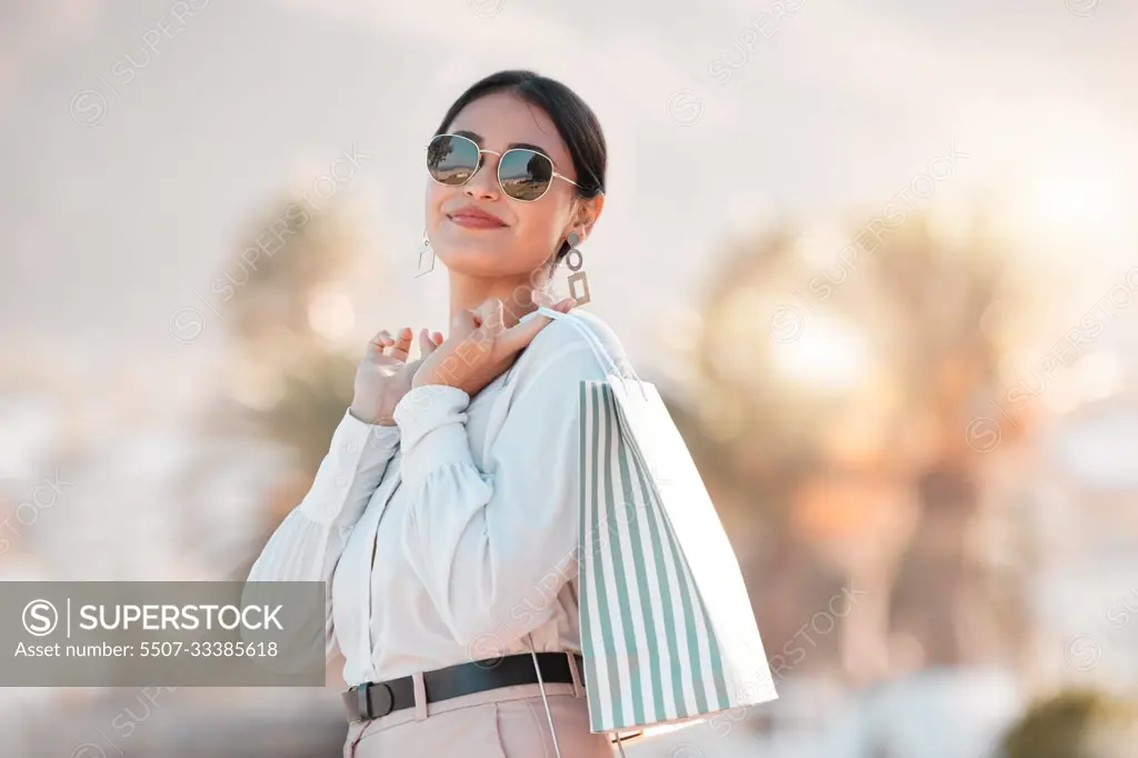 Retail shopping bag, urban woman and portrait travel for discount sales, market and outdoor sun in Dubai. Happy rich arab customer, consumer and wealthy person with sunglasses buying luxury fashion