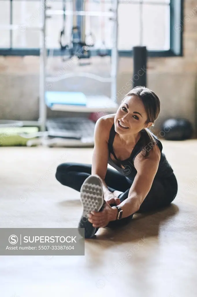 Portrait, smile and woman stretching, fitness and workout goal with balance, stress relief and happiness. Face, female person or athlete on the floor, stretch legs and training for wellness or health