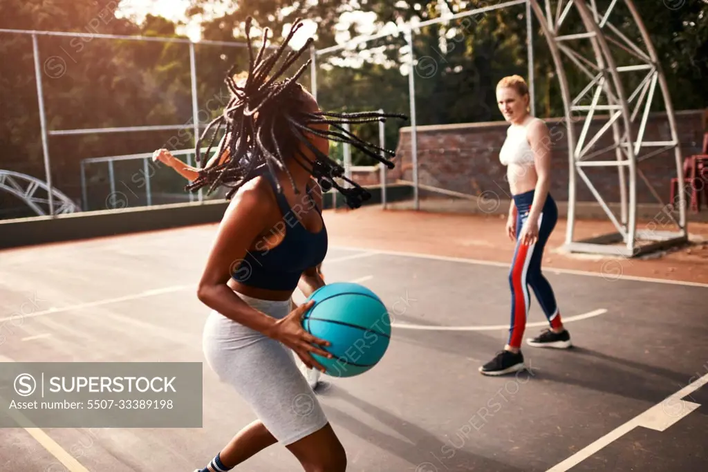 Can I score from here. a diverse group of sportswomen playing a competitive game of basketball together during the day.