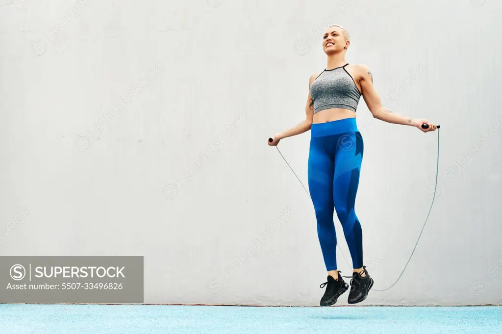 Jump, rope and woman skipping against space in stadium for sports, workout practice and cardio. Performance, health and body with female athlete training on track for strong, mockup and exercise