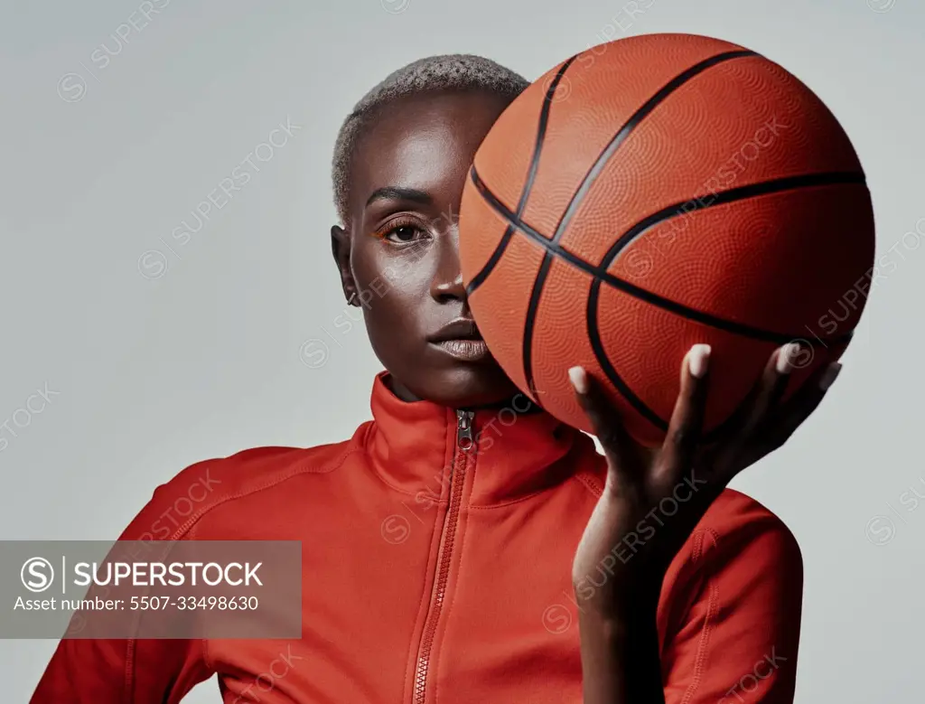 Call me the queen of the basketball court. Studio shot of an attractive young woman playing basketball against a grey background.