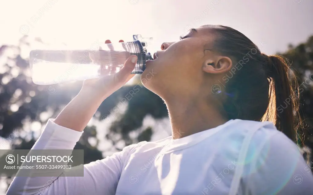 Drinking water, fitness and running with a sports woman outdoor for a cardio or endurance workout. Training, exercise and wellness with a female athlete taking a drink for hydration on a break