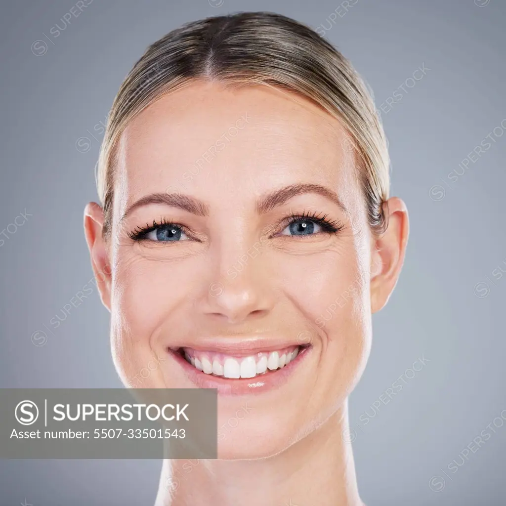 She has that timeless beauty. Studio portrait of an attractive mature woman  posing against a grey background. - SuperStock