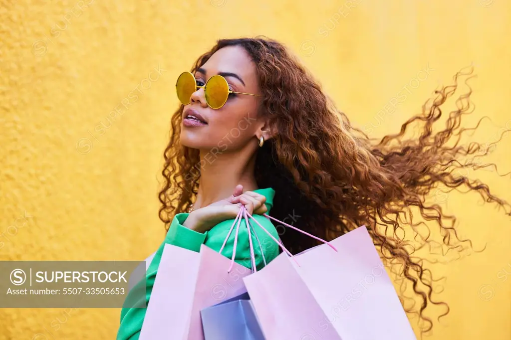 Wealth, posh and portrait of a woman with shopping bags for fashion, luxury sale and discount. Elegant, retail and rich girl in the city to shop, buying clothes and fashionable clothing on a wall