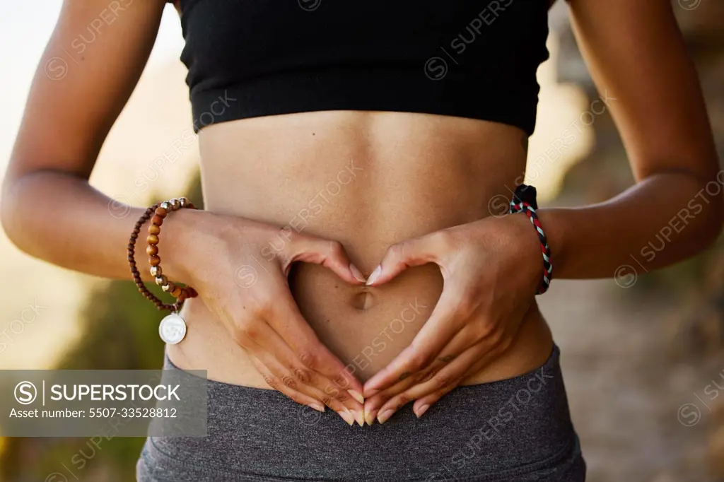 Woman, stomach and hand with heart in outdoor for exercise, diet, fitness and closeup. Female tummy, gut health and self love for wellness and training in the summer for healthy workout outside.