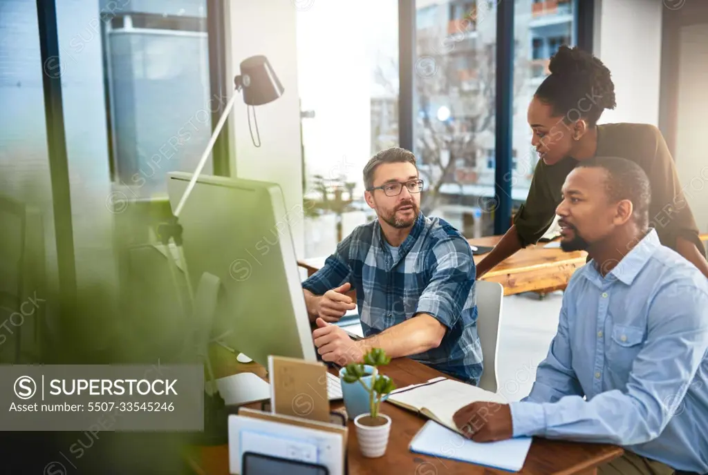 Coming together to achieve success. three businesspeople working around a computer in the office.