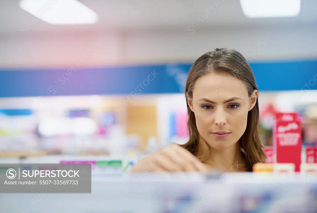 A young woman buying medicine in a pharmacy -The commercial designs displayed in this image represent a simulation of a real product and have been changed or altered enough by our team of retouching and design specialists so that they are free of any copyright infringements