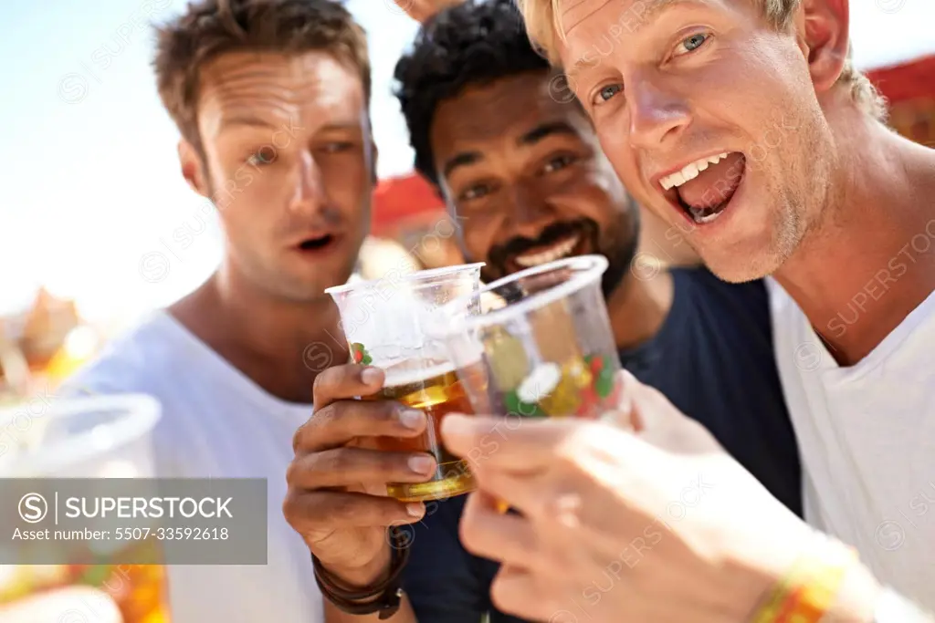 Let the partying begin. Three young men toasting their beers at a music festival.