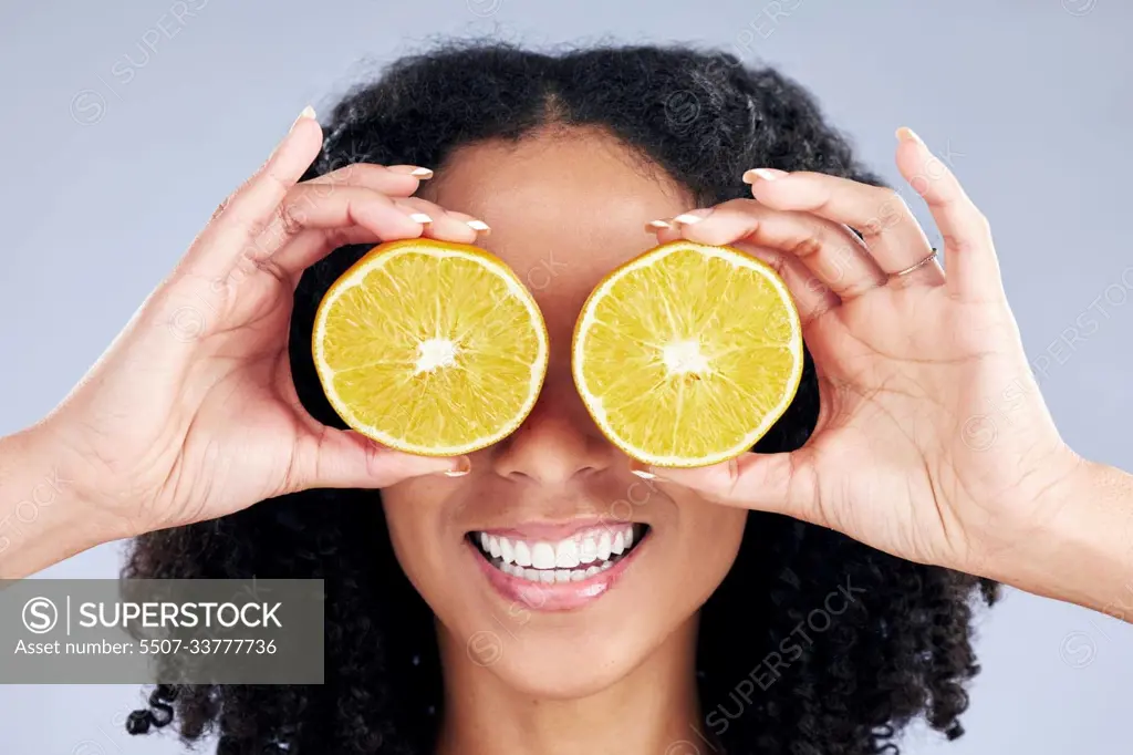 Woman, lemon eyes and skincare in studio for comic smile, health or nutrition for wellness by background. Girl, African model and fruits for diet, cleaning and cosmetic for beauty, self care or emoji