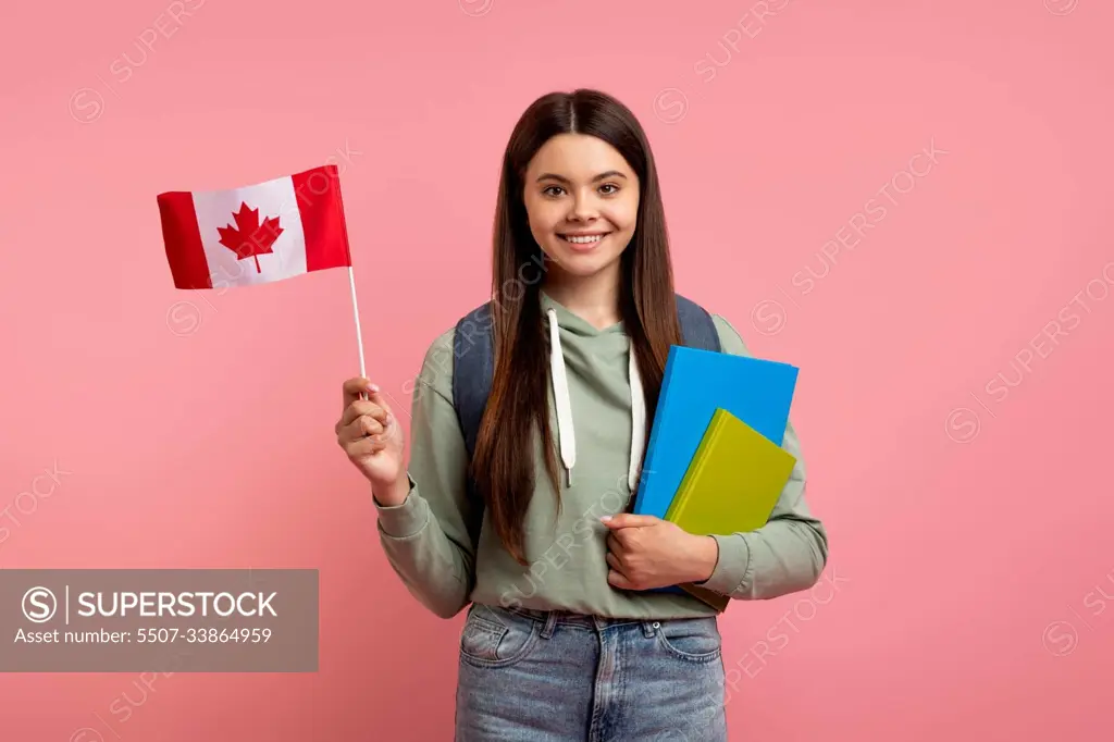 Study Abroad. Beautiful Teen Girl Holding Flag Of Canada And Workbooks