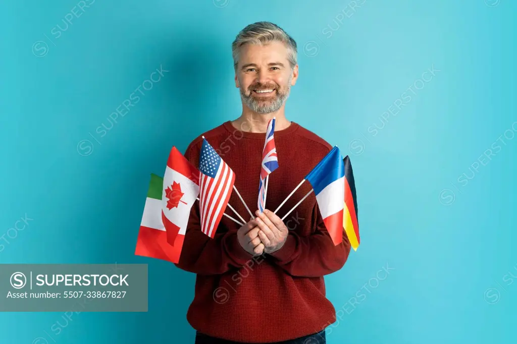 Cheerful grey-haired mature man holding flags of different countries