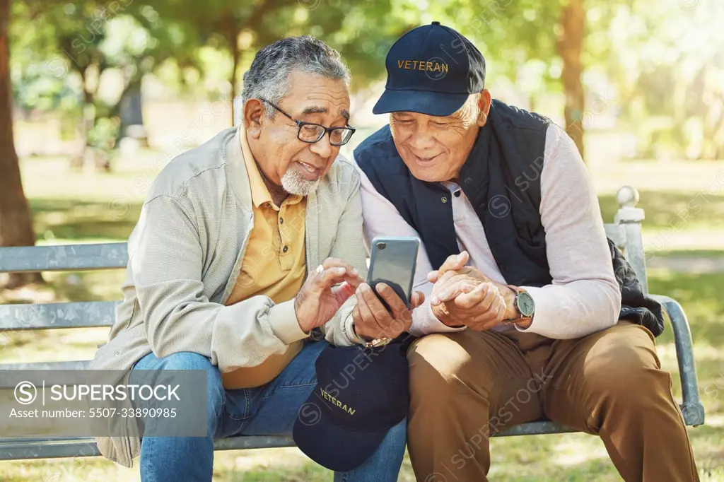 Elderly men, friends and phone in park, reading and army memory with thinking, relax and sunshine. Senior military veteran, smartphone social media and talk on bench, nostalgia and remember service